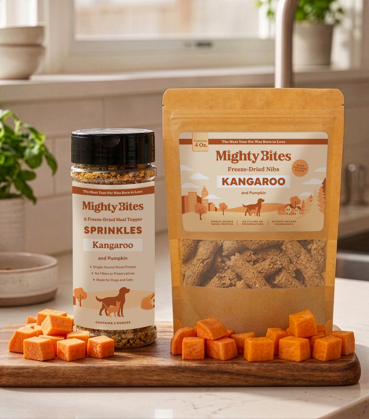 A jar of Mighty Bites Kangaroo and pumpkin Sprinkles and a stand-up pouch of Mighty Bites Freeze-Dried Nibs also in Kangaroo are displayed on a wooden cutting board with cubes pumpkin in a bright kitchen setting. A dog or cat treat and meal topper. 